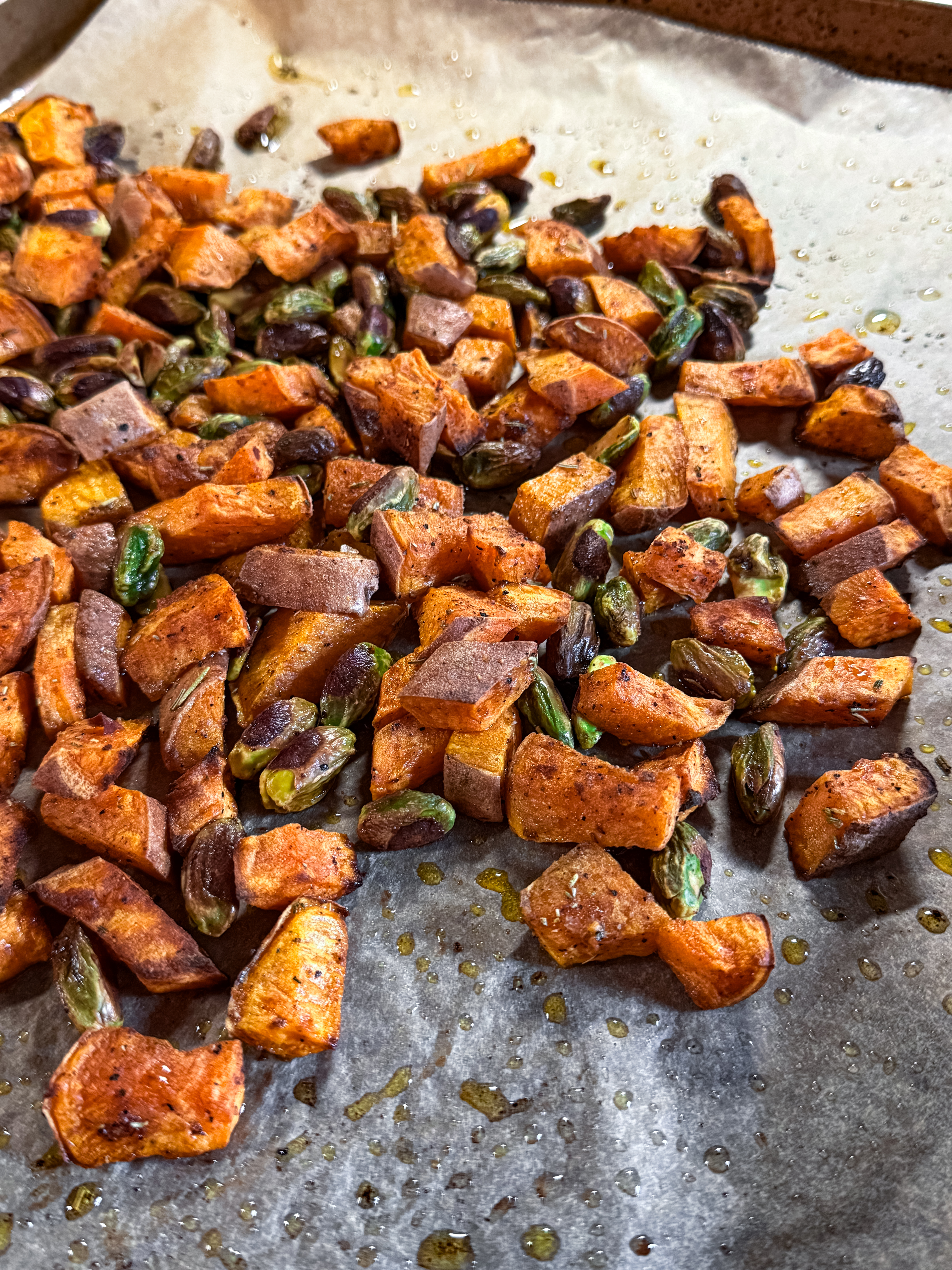 Roasted sweet potatoes with pistachios on parchment paper — healthy salad topping or side dish